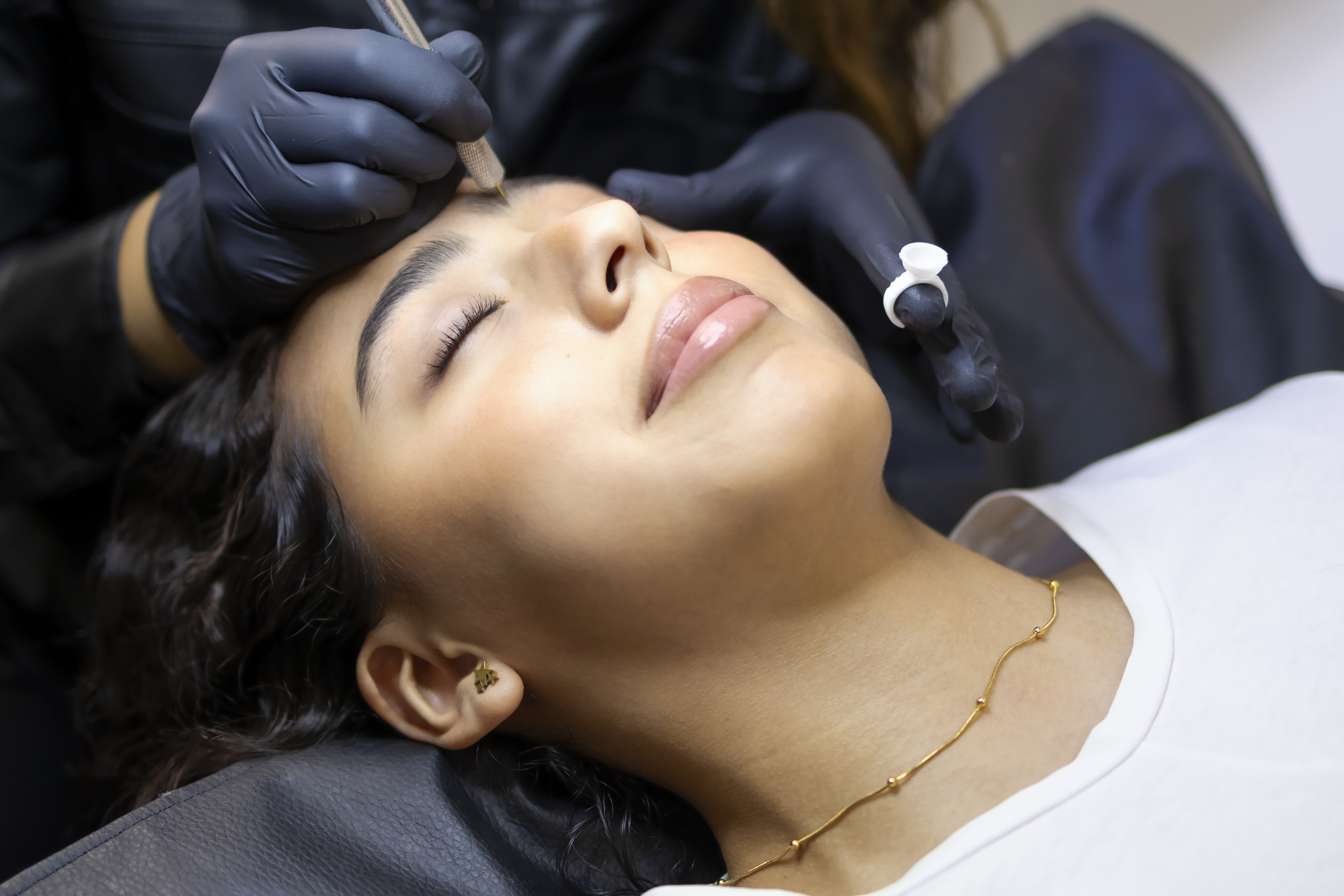 Stylist doing the eyebrows of a girl